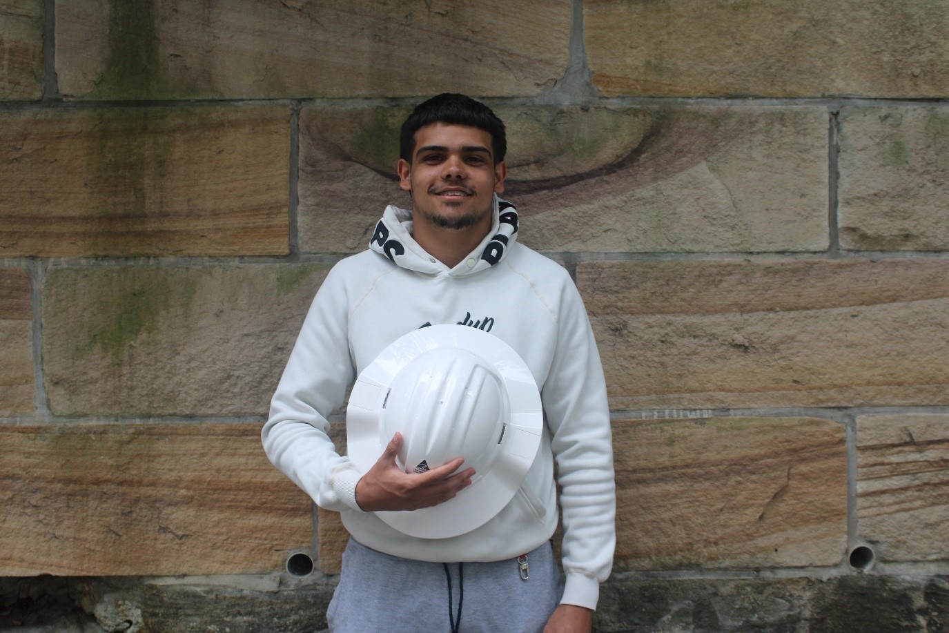 A person holding a hard hatDescription automatically generated